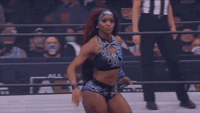 a female wrestler is standing in a ring with a referee behind her