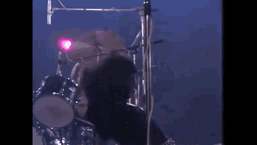 a man is standing on a stage in front of a drum set and a microphone .