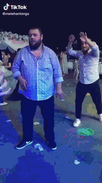 a tiktok video of two men dancing with a green circle on the ground