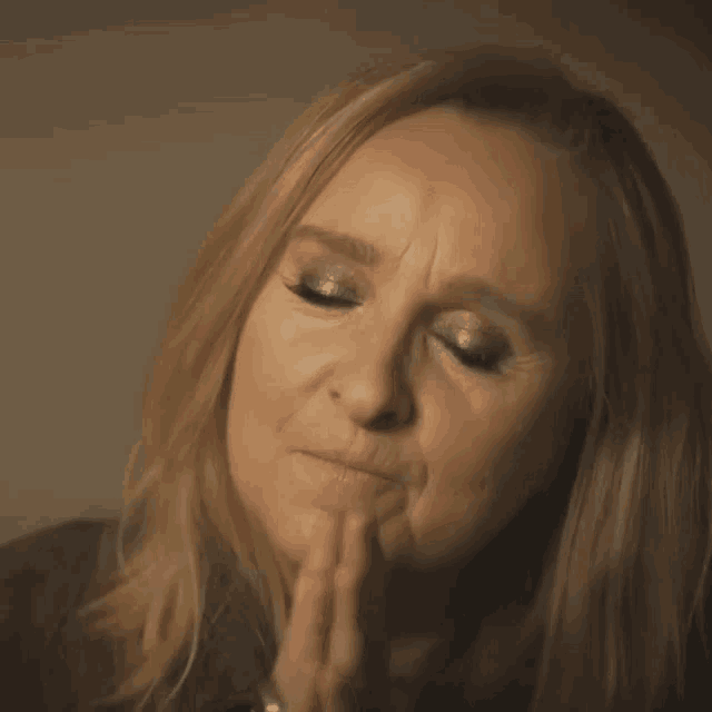 a close up of a woman with her hands folded in front of her face