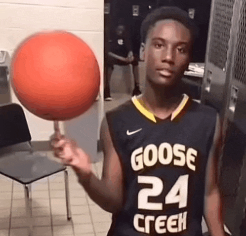 a young man in a goose jersey is holding a basketball in his hand .
