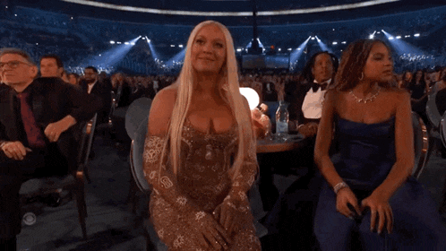 a woman with blonde hair is sitting in a stadium with other people .