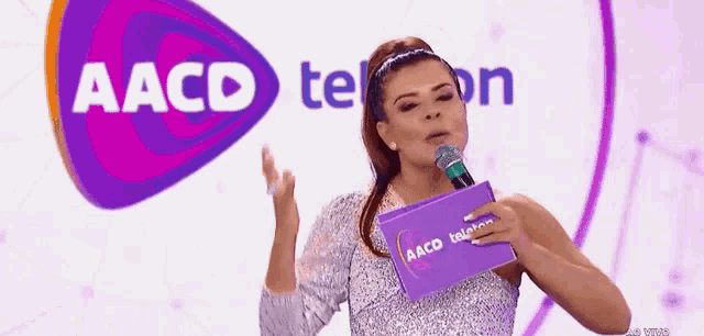 a woman is holding a microphone in front of a aacd logo