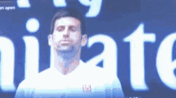 a man in a white shirt is standing in front of an emirates sign