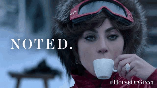 a woman wearing a fur hat and goggles drinking from a cup that says noted