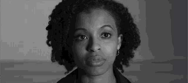 a black and white photo of a woman with curly hair and earrings .