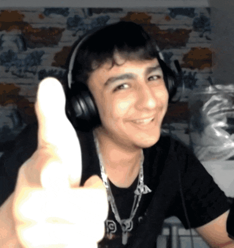 a young man wearing headphones giving a thumbs up sign