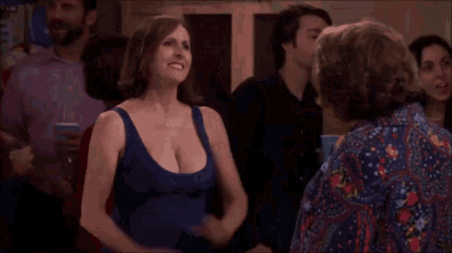 a woman in a blue tank top is standing in a crowd of people