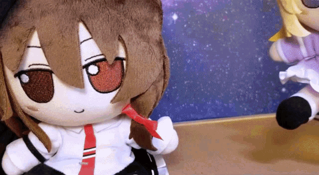 two stuffed dolls are sitting on a table and one is wearing a tie