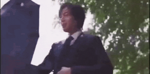 a man in a suit and tie is holding a black umbrella in the rain .