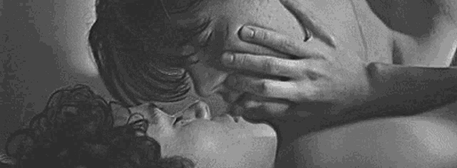 a black and white photo of a couple kissing .