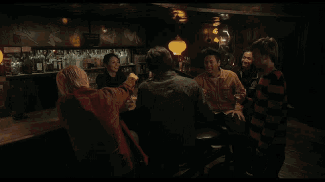a group of people sitting at a bar with cheers written on the screen