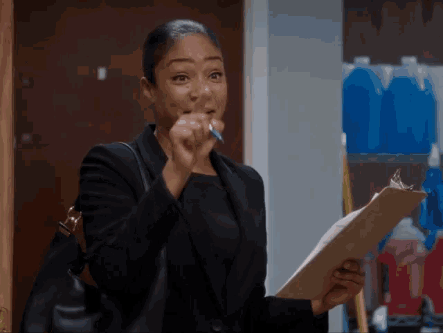 a woman in a black suit holds a clipboard and a pen