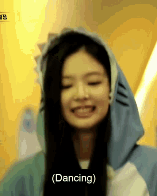 a woman wearing a shark hoodie is smiling and dancing .