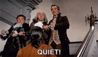 a group of men are standing on a set of stairs and a woman is standing in front of them and saying quiet .