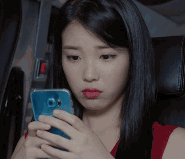 a woman in a red top is looking at her cell phone