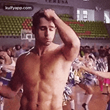 a shirtless man is standing in front of a crowd of people in a stadium .