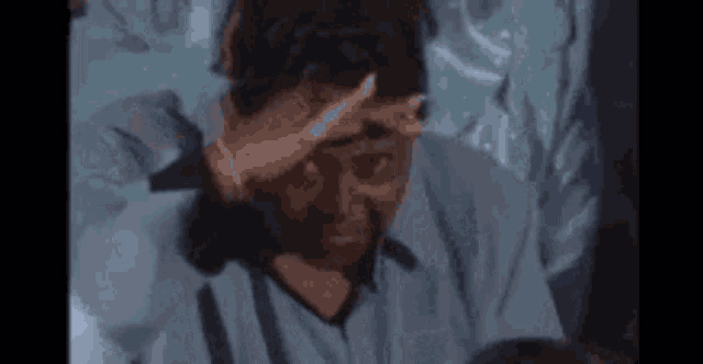 a man is holding his hand to his forehead while looking at a cell phone .