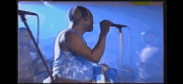 a man is singing into a microphone on a stage in front of a crowd .