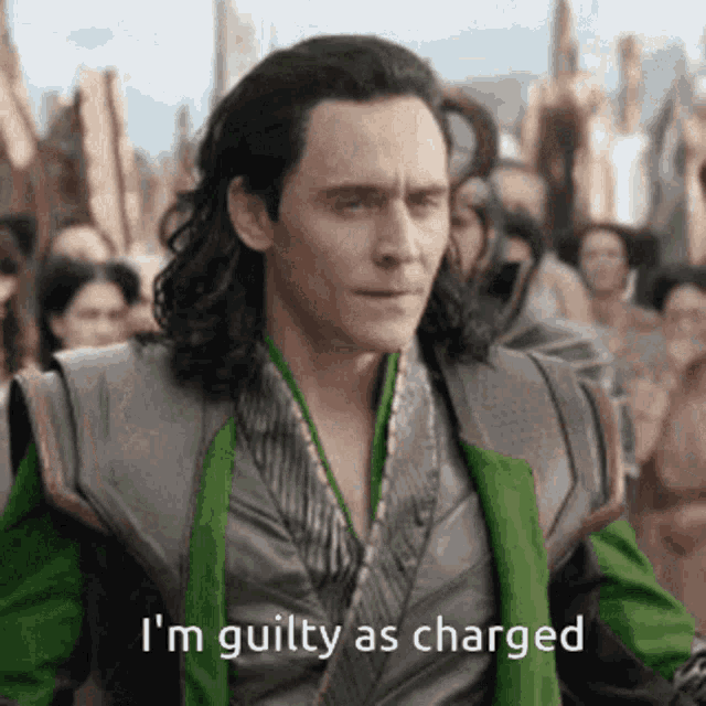 a man with long hair is standing in front of a crowd and says i 'm guilty as charged