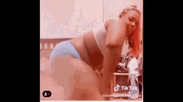 a woman in a white top and blue underwear is kneeling down on a bed .