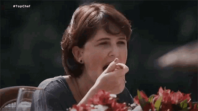 a woman is sitting at a table eating a piece of food with a fork .