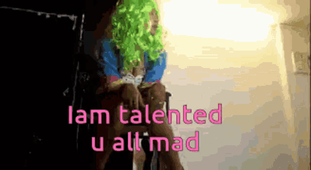 a woman in a green wig sits in a chair with the words " i am talented u all mad " written in pink