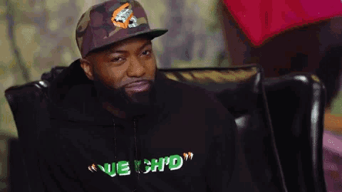 a man with a beard is wearing a hat and a hoodie that says " nuechd "