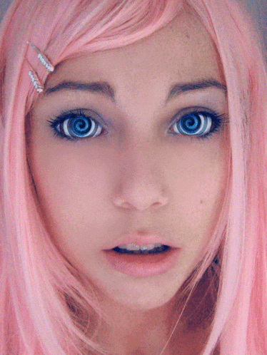a close up of a girl 's face with pink hair and blue hypnotic eyes