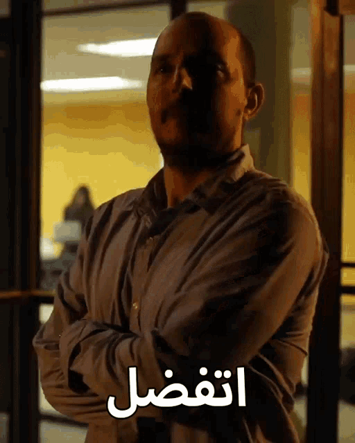 a man stands with his arms crossed in front of a sign that says ' aفضل '