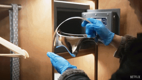 a person wearing blue gloves takes something out of a safe