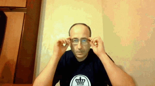 a man wearing glasses and a crown on his shirt