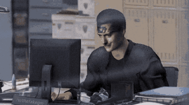 a man is sitting at a desk with a computer and a sign that says " authefakegm " on it