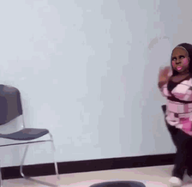 a woman in a pink shirt and black pants is standing next to a chair