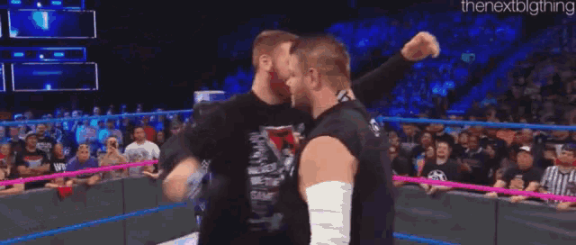 a couple of men hugging each other in a wrestling ring .