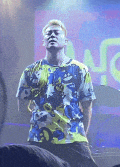 a man in a colorful shirt is standing in front of a screen that says nc