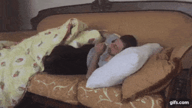 a man is sleeping on a couch with a black cat .