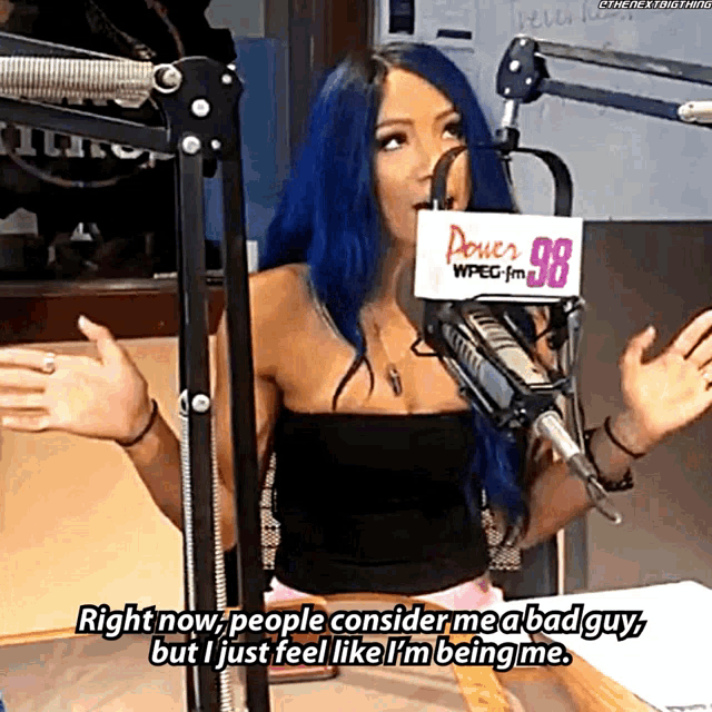 a woman with blue hair is talking into a microphone with a sign that says power 98 on it