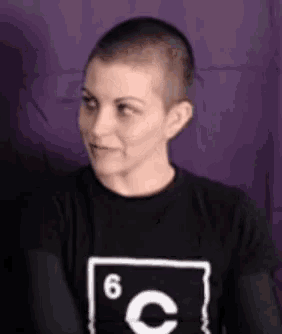 a woman with a shaved head is wearing a black t-shirt with the number 6 on it .