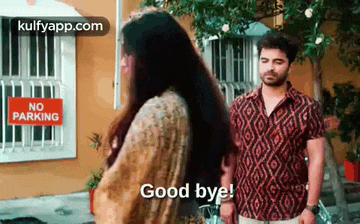 a man and a woman are standing in front of a no parking sign and saying good bye .