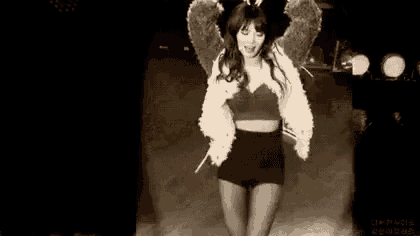 a black and white photo of a woman wearing angel wings and a fur jacket .
