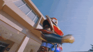 a man in a red and blue costume is standing in front of a building