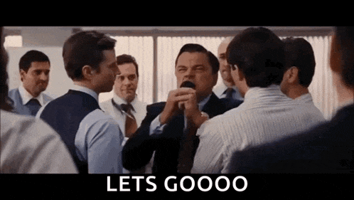 a group of men are standing in a room talking to each other and a sign that says lets goooo .