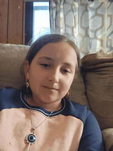 a young girl wearing a necklace with a key on it