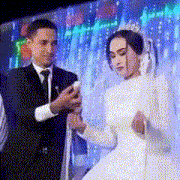 a man in a suit and tie is taking a picture of a bride and groom .
