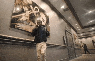 a man smoking a cigarette in a hallway with a sign on the wall that says exit lane