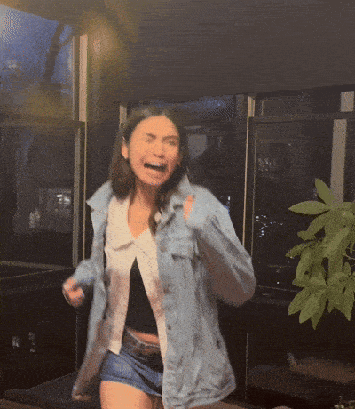 a woman wearing a denim jacket and shorts is laughing with her mouth open