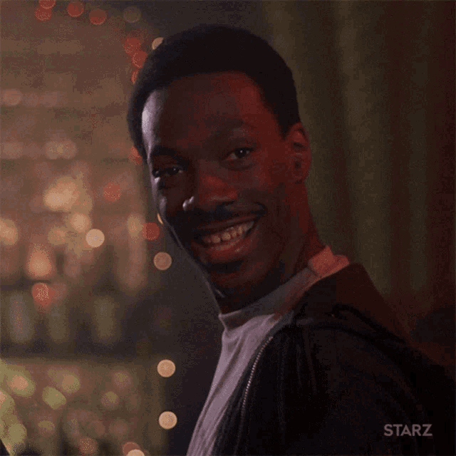 a man is smiling in front of a starz sign
