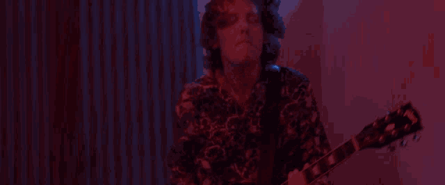 a man is playing an electric guitar in a dark room with red lights .