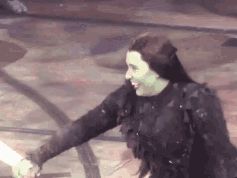a woman in a witch costume is holding a person 's hand and smiling .